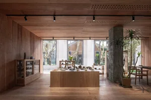 A minimalist coffee shop interior with wooden and concrete elements, showcasing various display items.