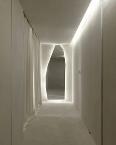 A minimalist corridor with a concrete wall and a lit opening at the end, creating a modern and sleek ambiance.