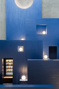 A minimalist retail shelf with books illuminated by spherical lights.