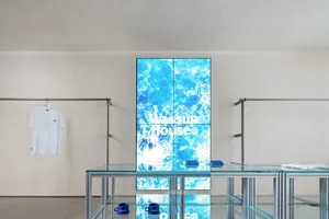 A minimalist retail storefront featuring a glass display case with a blue ocean-themed logo on a digital screen.