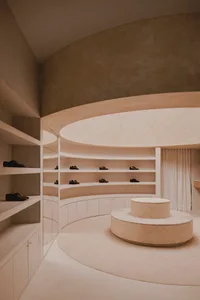 A minimalist display featuring shoes on concrete shelves and a concrete pedestal.