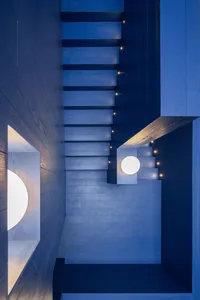A minimalist staircase with blue tones, featuring light fixtures and wooden steps.