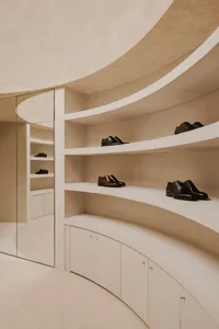 A modern, minimalist shoe closet with concrete shelving and cabinets, showcasing sleek, black leather dress shoes.