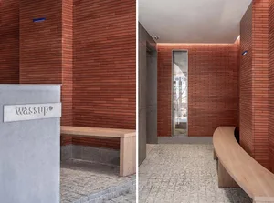 A modern lobby with red brick walls and a wooden seating area.
