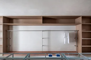 A modern clothing display featuring wooden shelves and glass railings, showcasing minimalist aesthetics.