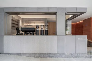 A modern coffee shop with a minimalist design featuring a concrete counter and industrial aesthetic.