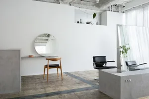 A modern hair salon featuring a minimalist design with concrete flooring and walls.