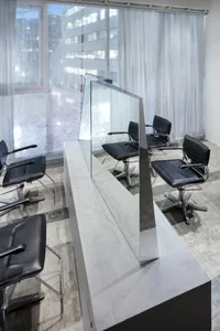 Modern hair salon featuring a sleek, glass-top counter with black chairs.