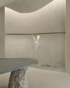 簡約現代的室內空間，設有混凝土桌與牆面，衣桿上懸掛著一件白色洋裝。