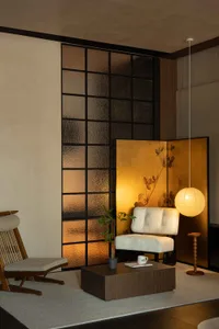Modern living room featuring glass walls, fabric seating, and wooden flooring.