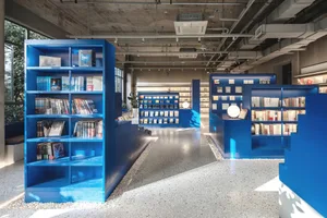 現代圖書館室內，藍色書架上擺放書籍與雜誌。