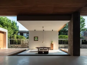 A modern living room featuring a concrete platform with minimalist furniture and large windows.