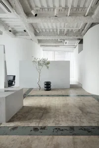 A minimalist modern office space with concrete flooring and minimalist furniture.