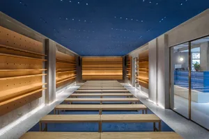 Modern retail space featuring wood and concrete walls with shelving and seating arrangements.
