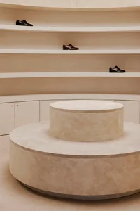 A minimalist shoe display composed of stone and concrete in a modern interior design setting.
