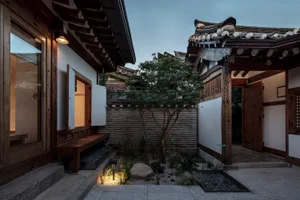 A traditional Korean house with wooden walls, tiled roofs, and a small courtyard garden.