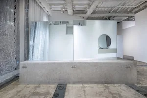 An abstract, minimalist installation featuring large sheets of frosted glass mounted on a concrete pedestal.