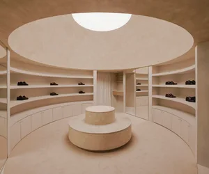A modern circular closet with granite columns, featuring a central pedestal and shelves lined with black shoes.