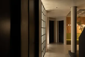 A modern minimalist hallway with concrete flooring and a glass partition.