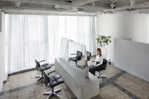 A modern salon interior with concrete walls, minimalist design, and black leather chairs.