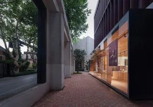 A brick and concrete storefront with large glass windows displaying merchandise in a retail setting.