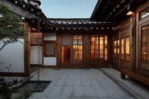 A traditional wooden residence interior with a courtyard and lit rooms.