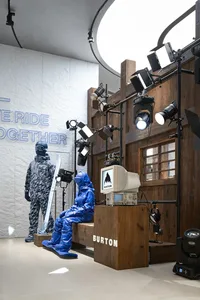 A stage setup with lighting equipment and uniforms, featuring a screen displaying the word 'Burton'.