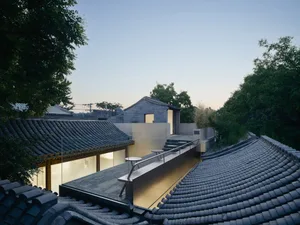A modern house with a black tiled roof during sunset.