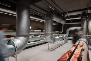 Industrial retail space with metal pipes, concrete floors, and glass display cases.