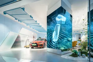 A minimalist car showroom with a glass wall and a red BMW car on display.