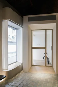 A minimalist entrance featuring a glass door with a bicycle parked inside the room.