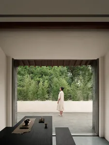 A minimalist interior design featuring a modern wood table with greenery outside the window.
