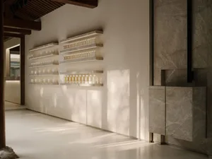 A minimalist interior design showcasing a marble counter displaying various perfumes and candles.
