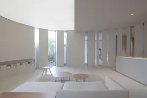 A minimalist white interior design featuring concrete and wood elements.