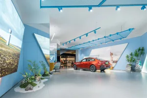 Modern car exhibition display with blue walls, glass wall, and orange car.