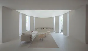 A minimalist living room with concrete walls, a cream-colored sofa, and a rug.