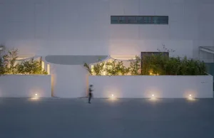 A modern exterior building facade with concrete walls and glowing lights at dusk.