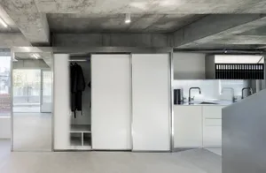 Modern, minimalist kitchen with concrete finishes and white cabinets.