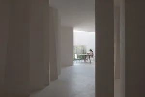 A minimalist living room with a concrete floor and white walls.