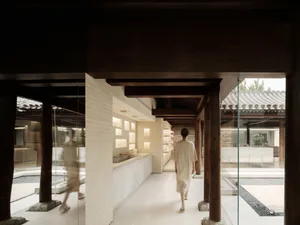 A modern public space featuring wooden beams, porcelain tiles, white marble, and sleek kitchen furniture.