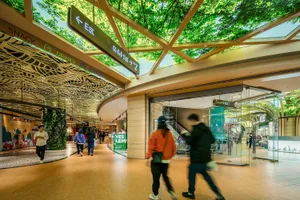 購物者在現代購物中心內，抬頭欣賞玻璃天花板與綠意植栽