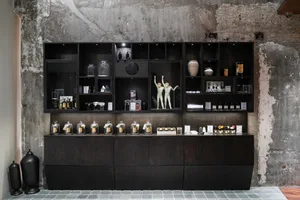 A retail storefront displaying glass, dark wood, and concrete accessories in an upscale, modern setting.