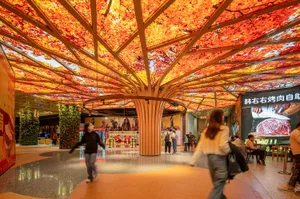 People walking inside a shopping center with LED lights illuminating the ceiling.