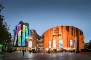 A modern shopping mall with a multicolor metal-clad exterior and illuminated signage.