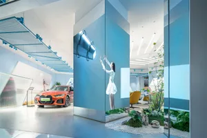 A car showroom featuring a modern interior design with blue lighting, metal accents, and green plants.