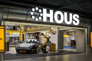 現代汽車展示店內，黑色保時捷跑車陳列於高級地板上，搭配黃色點綴與混凝土金屬飾面。