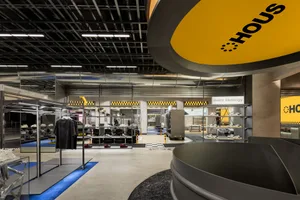 A modern fashion retail store with metallic finishes, concrete flooring, and glass displays.