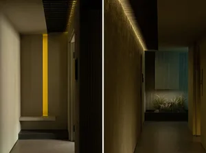 A minimalist hallway with concrete walls and floor, illuminated by subtle lighting from the ceiling.