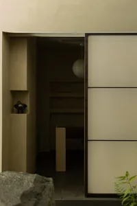 A minimalist entrance space with a door, shelves, and a hanging light fixture.