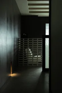 A minimalist interior design featuring a glass wall panel, with light filtering through